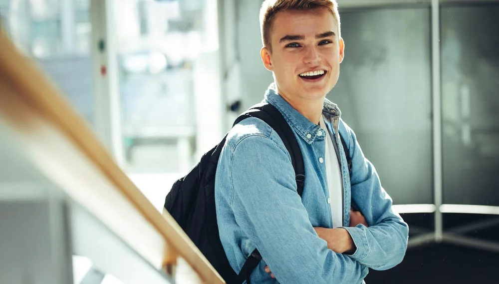 Young,Man,In,College,Campus,Standing,With,Arms,Crossed,Smiling